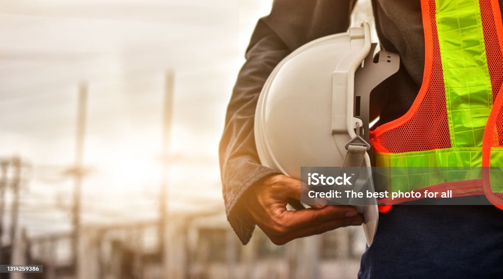 Home technician holding white hat safety hard hat sunlight background